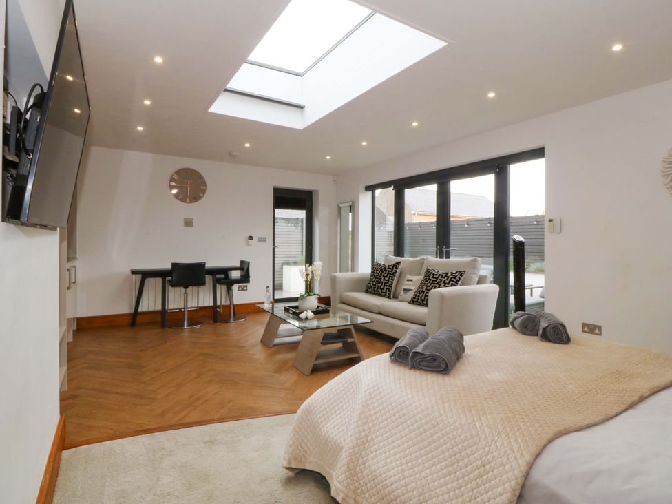 A living room with a sofa, glass table, and a dining table at Lodge in Llangefni