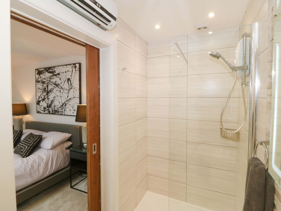 A bathroom with a shower and a view of a bedroom at Lodge Llangefni