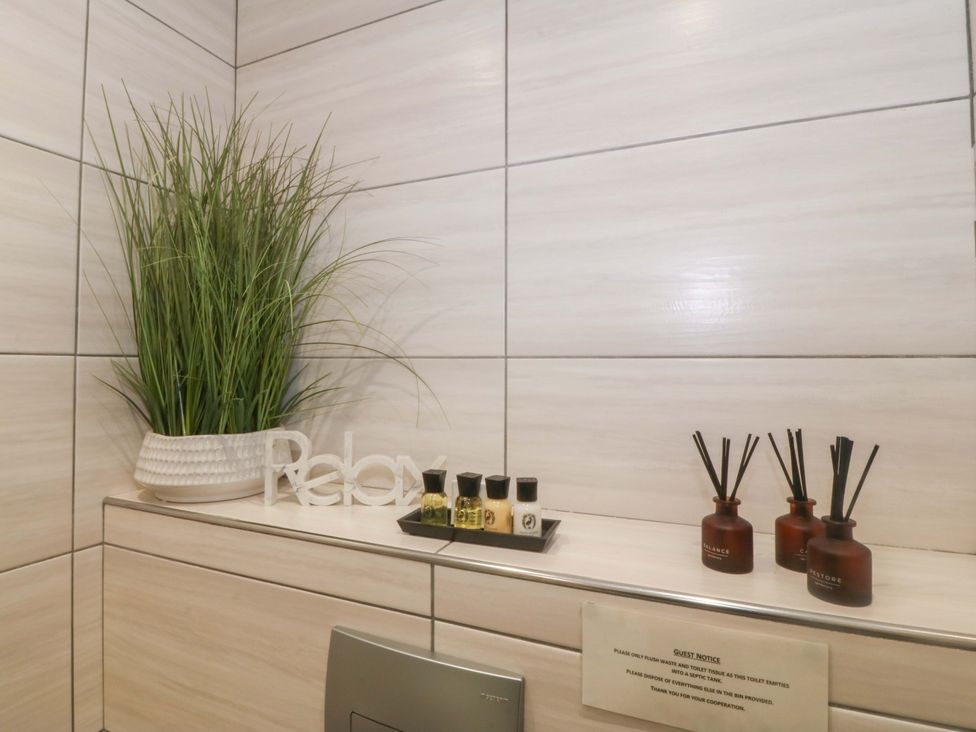 A bathroom with potted plant and scented oils at Lodge in Llangefni