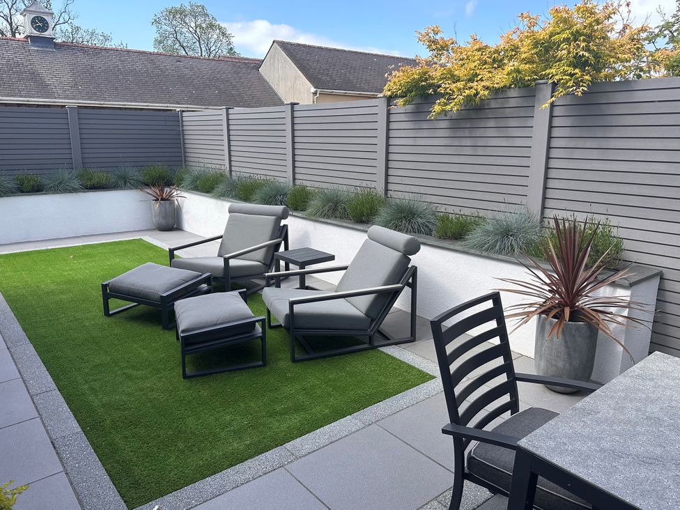 A patio with lounge chairs and a dining table at Lodge in Llangefni