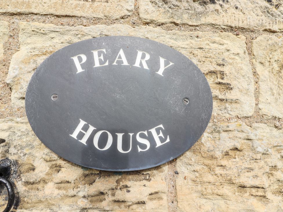 A sign displaying Peary House on a stone wall at Peary House in Alnwick