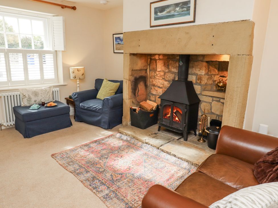 A living room with a fireplace and two seating areas at Peary House in Alnwick