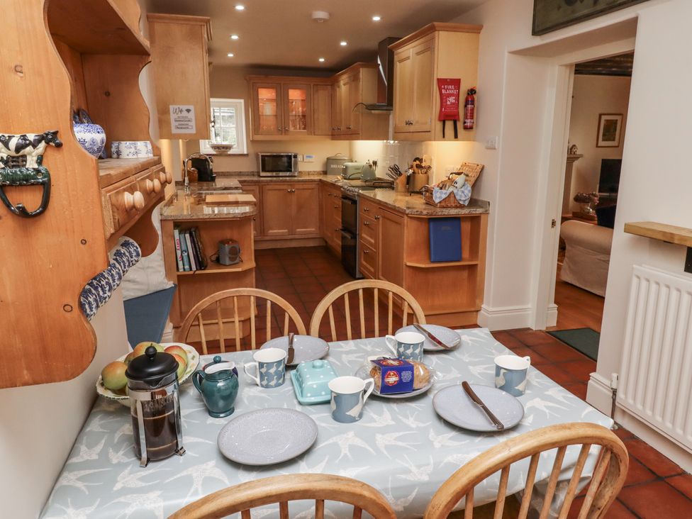 A kitchen with wooden cabinets and dining table at Peary House in Alnwick