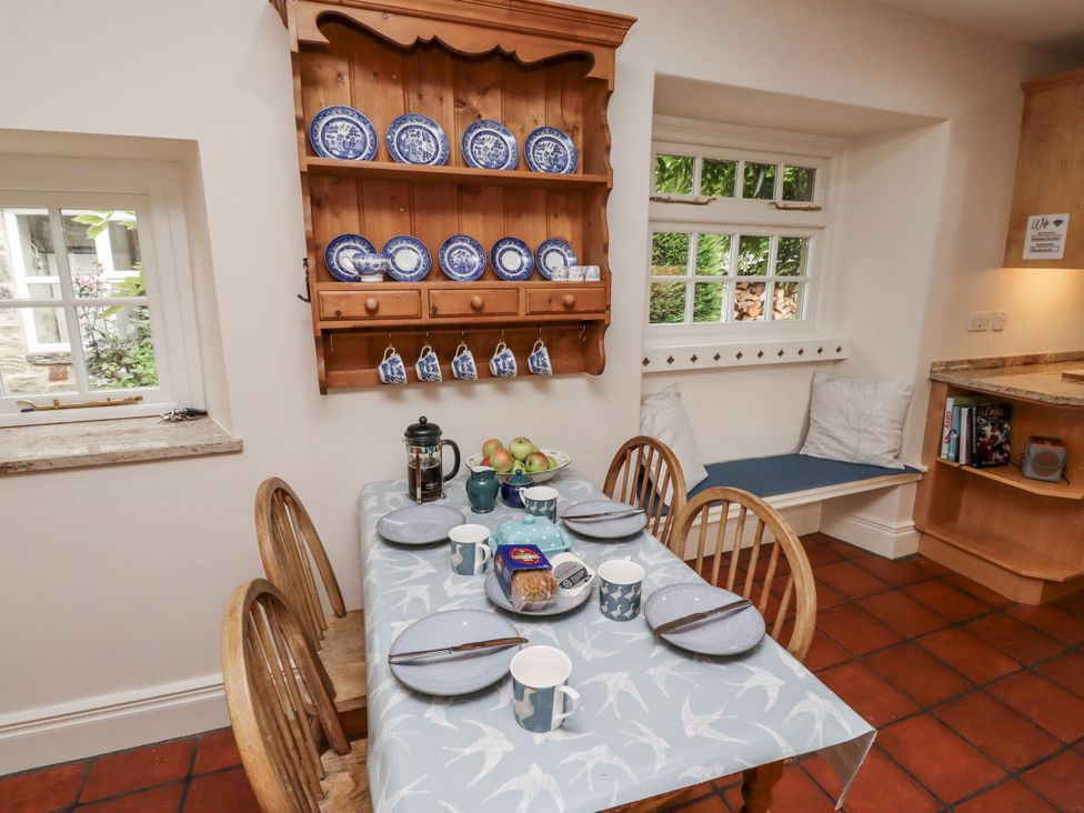 A kitchen with a table set for breakfast with dishes and apples at Peary House in Alnwick