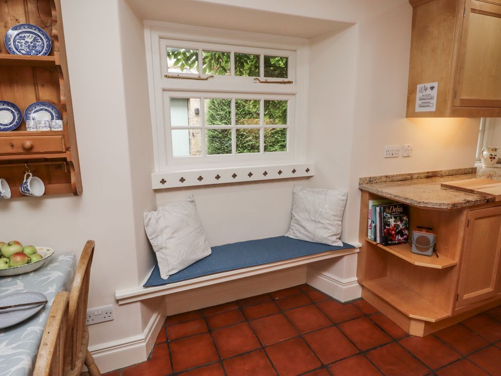 A kitchen with a window seat and a shelf displaying dishes at Peary House in Alnwick