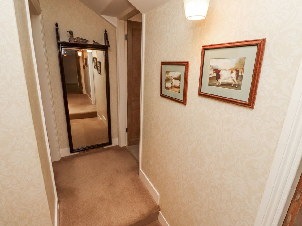 A hallway with a mirror and framed pictures at Peary House in Alnwick
