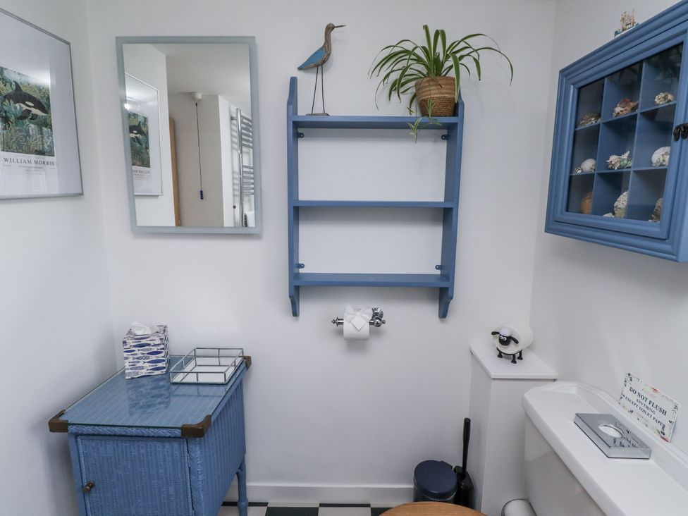 A bathroom with a mirror, toilet, and blue shelving at Peary House, Alnwick