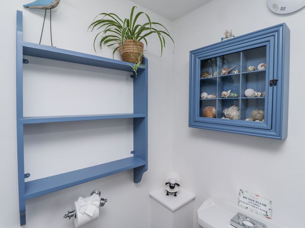 A bathroom with a shelf, cabinet, and toilet at Peary House in Alnwick