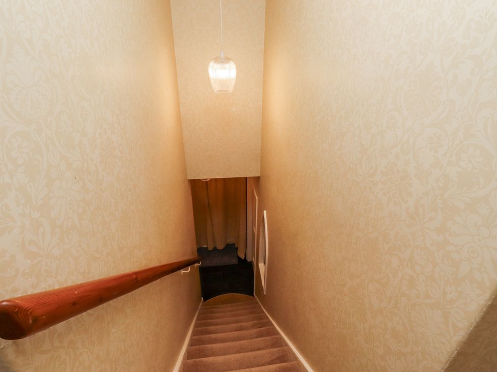 A staircase with a handrail and light fixture at Peary House in Alnwick
