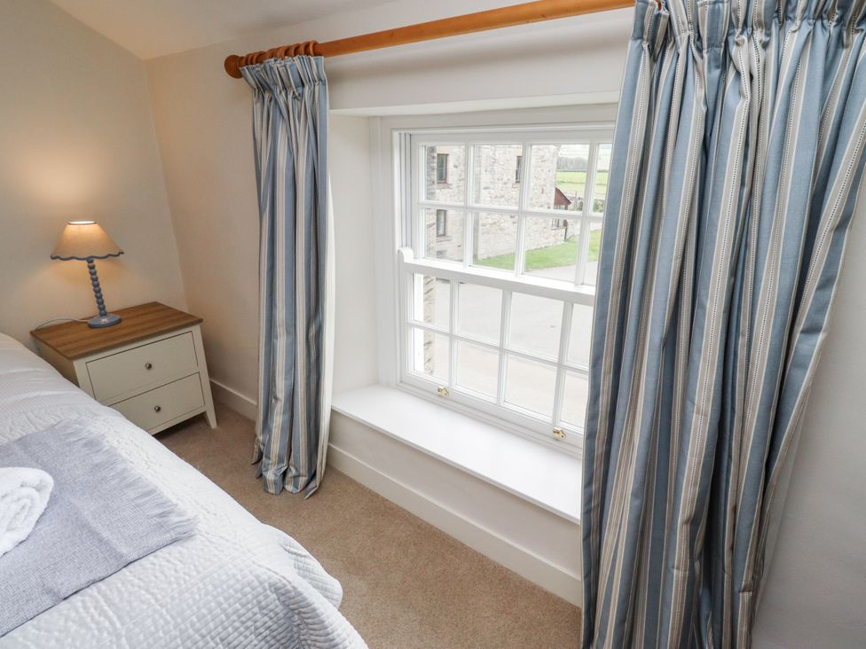 A bedroom with a window and bedside table at Peary House in Alnwick