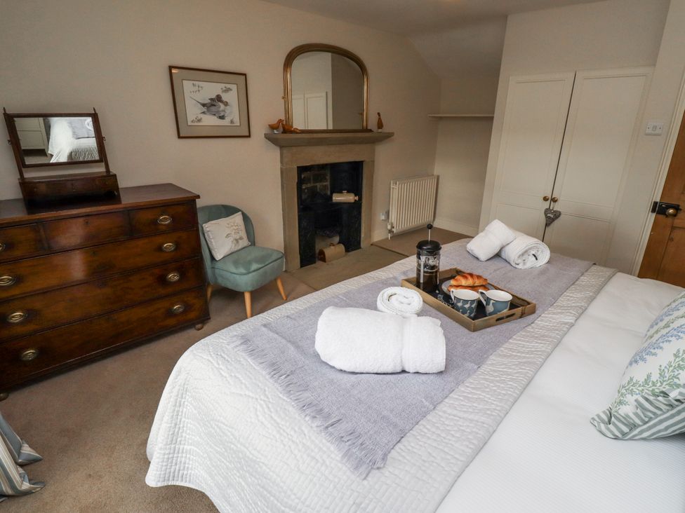 A bedroom with a bed, dresser, and fireplace at Peary House in Alnwick