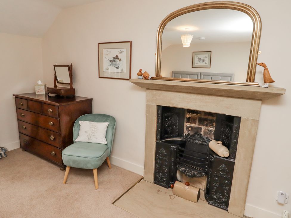 A living room with a fireplace, dresser and chair at Peary House in Alnwick
