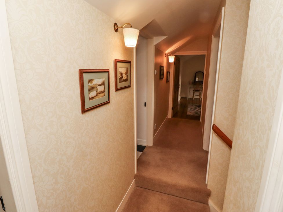 A hallway with pictures on the walls and a light fixture at Peary House in Alnwick