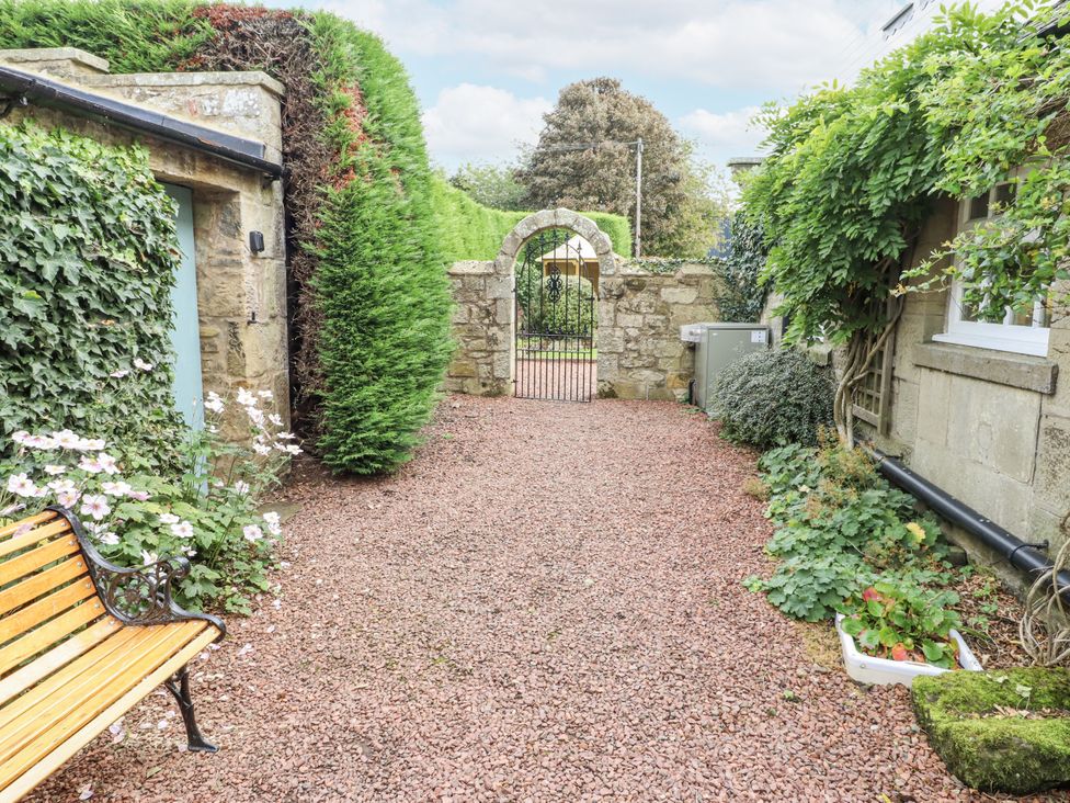 A garden with a gravel pathway and a gate at Peary House in Alnwick