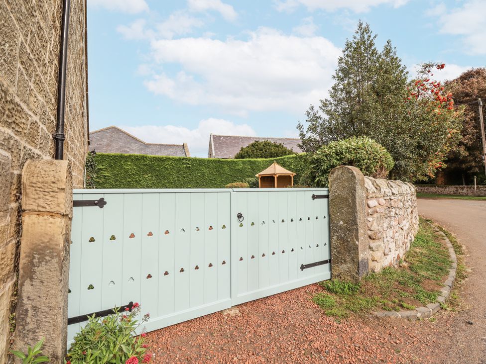 A gate with a stone wall and garden at Peary House in Alnwick