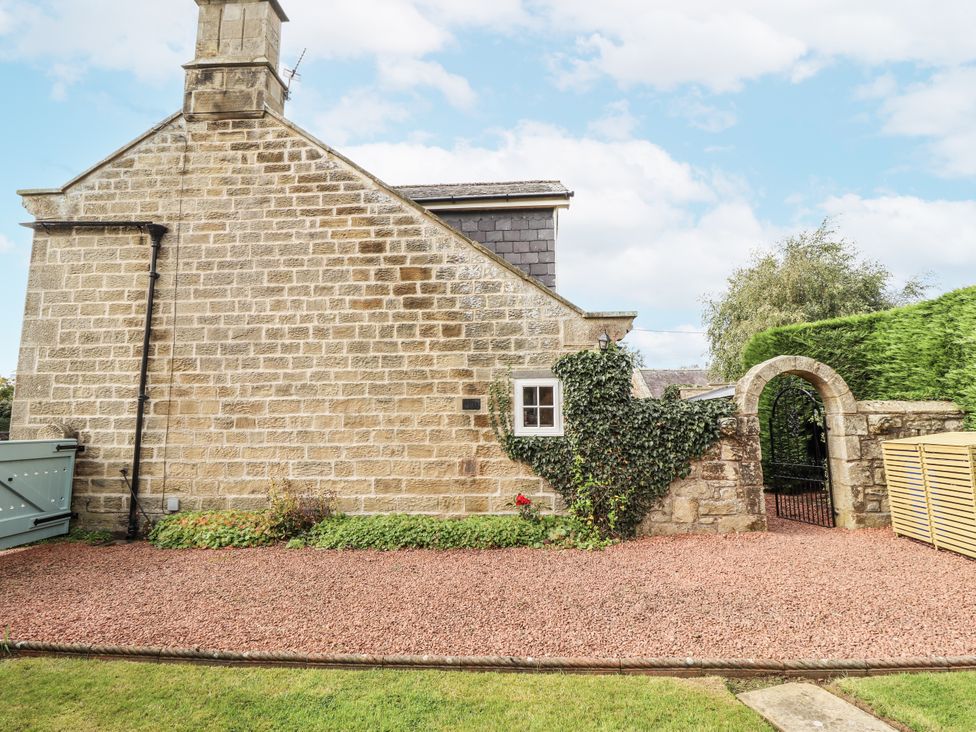 Exterior view of a stone house with a gravel area and a gate at Peary House in Alnwick