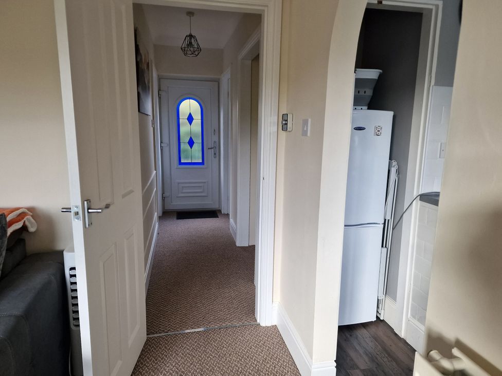 A hallway with a door and refrigerator at Golygfa Abergele