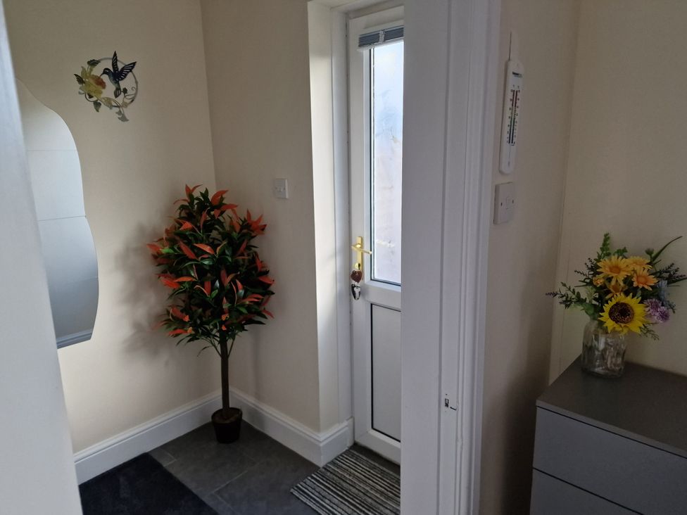 An entrance with a plant, flower vase, mirror and door at Golygfa in Abergele