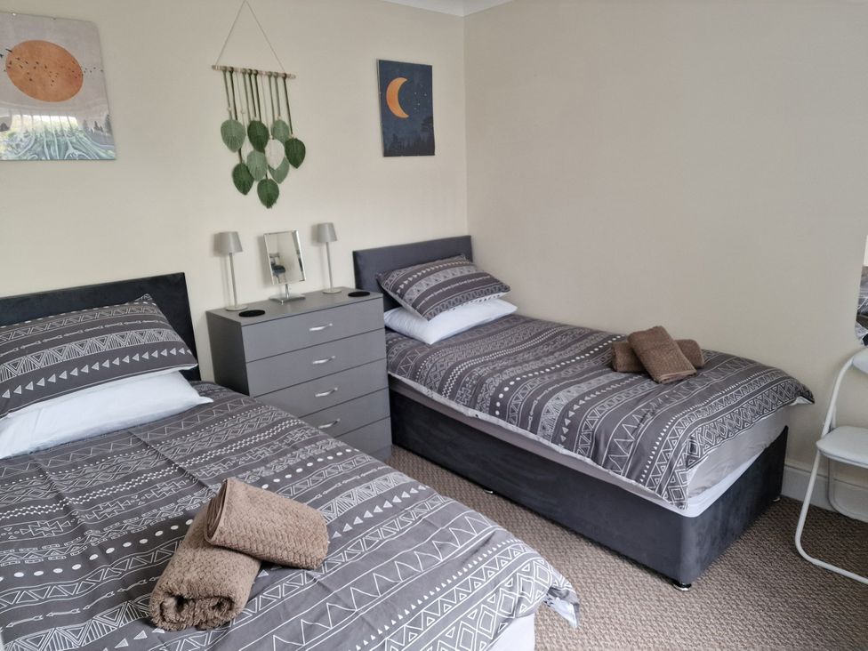 A bedroom with two beds and a nightstand at Golygfa in Abergele