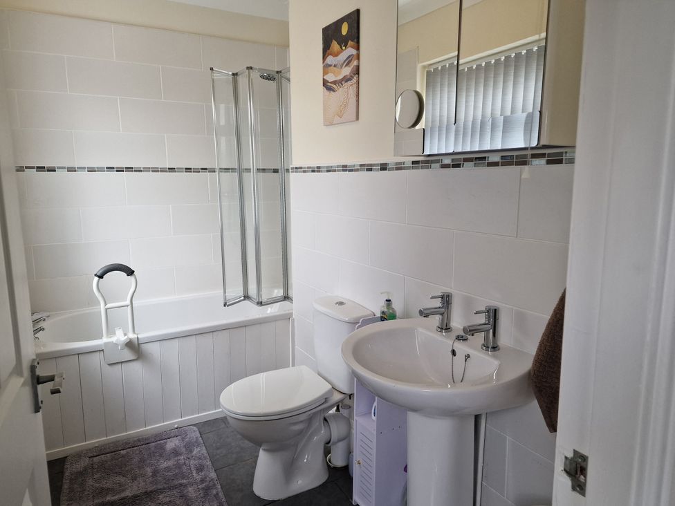 A bathroom with a bathtub, shower, toilet, and sink at Golygfa in Abergele