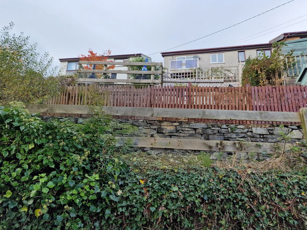 A garden with a stone wall and a wooden fence at Golygfa in Abergele