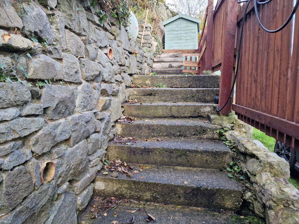 Stone steps leading up to a wooden fence and a shed at Golygfa Abergele