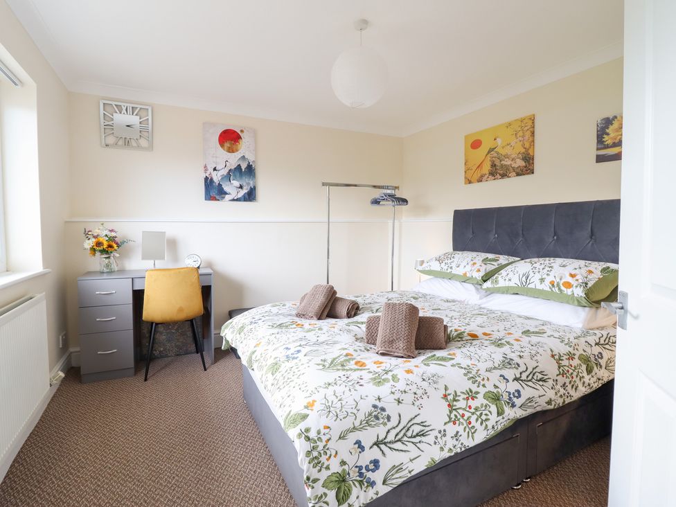 A bedroom with a bed, desk, chair and artwork at Golygfa in Pandy Tudur near Llanrwst