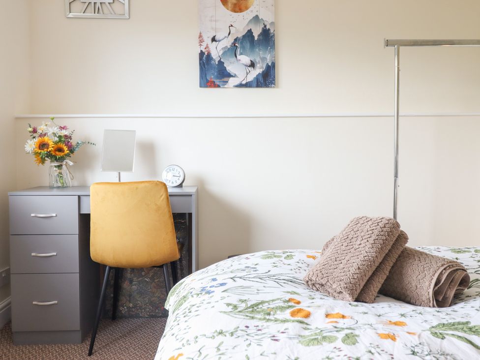 A bedroom with a bed, desk, and flowers at Golygfa, Pandy Tudur near Llanrwst