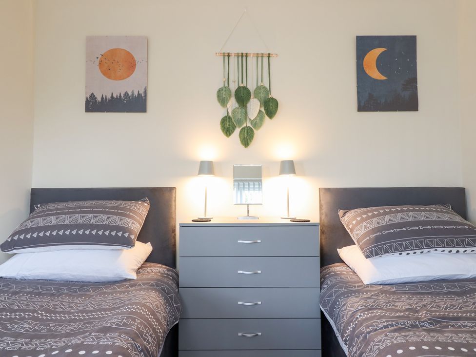 A bedroom with two beds and wall art at Golygfa in Pandy Tudur near Llanrwst