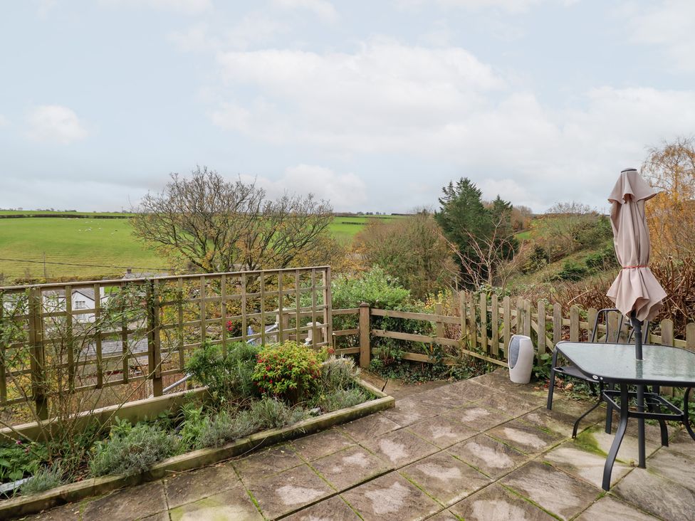 A garden with a table and umbrella overlooking a field at Golygfa Pandy Tudur near Llanrwst