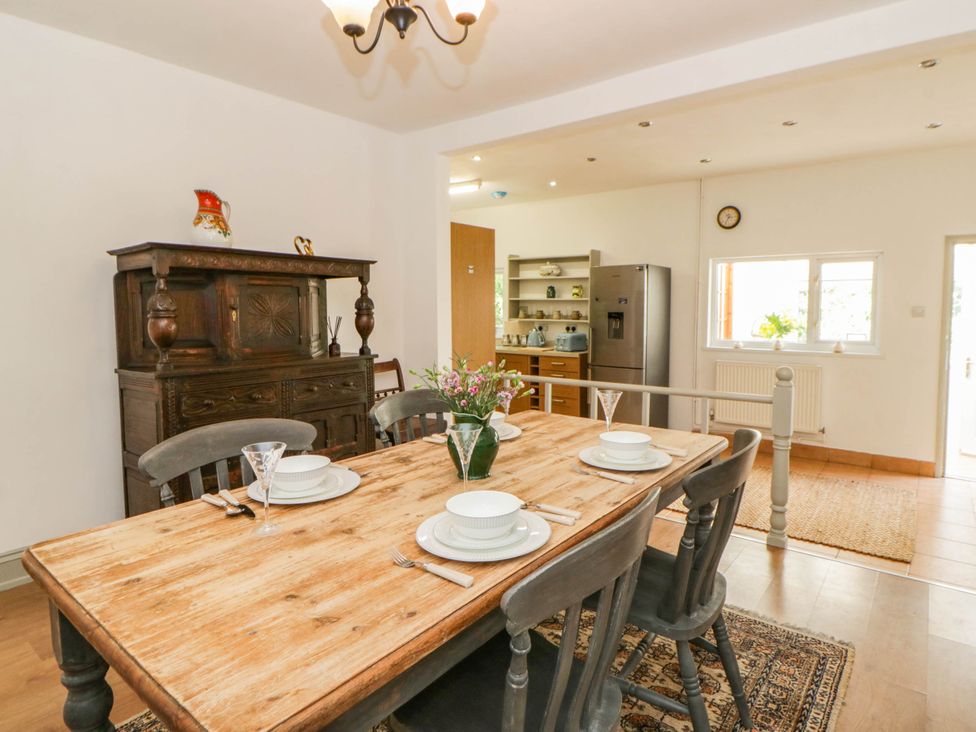 A dining room with a wooden table and sideboard at Llain in Cardigan