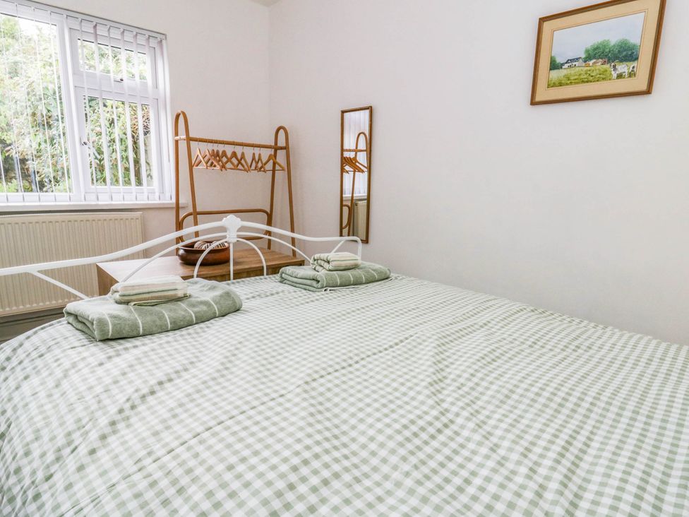 A bedroom with a bed and hanging area at Llain in Cardigan