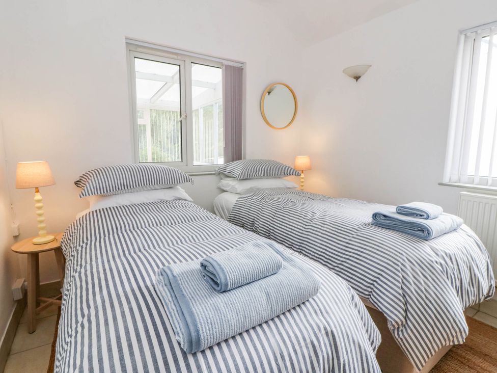 A bedroom with two beds and a bedside table at Llain in Cardigan