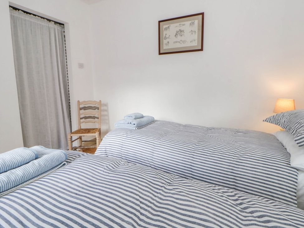 A bedroom with two beds and a chair at Llain in Cardigan