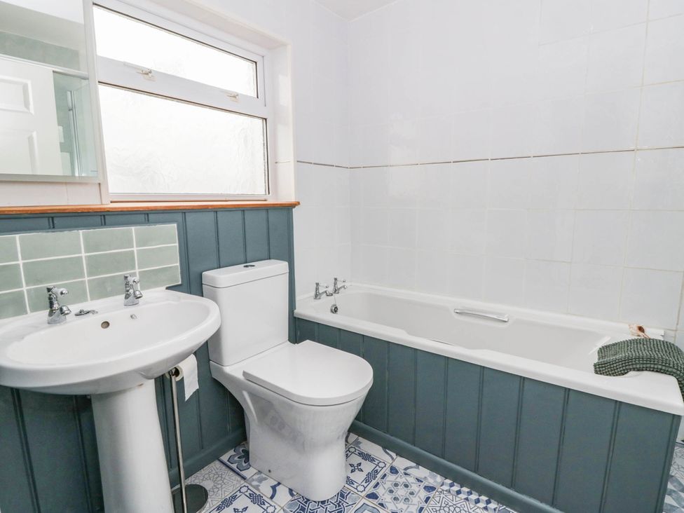 A bathroom with a bathtub, toilet, and sink at Llain in Cardigan