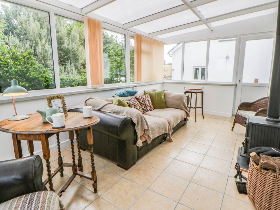 A conservatory with a sofa and table at Llain in Cardigan