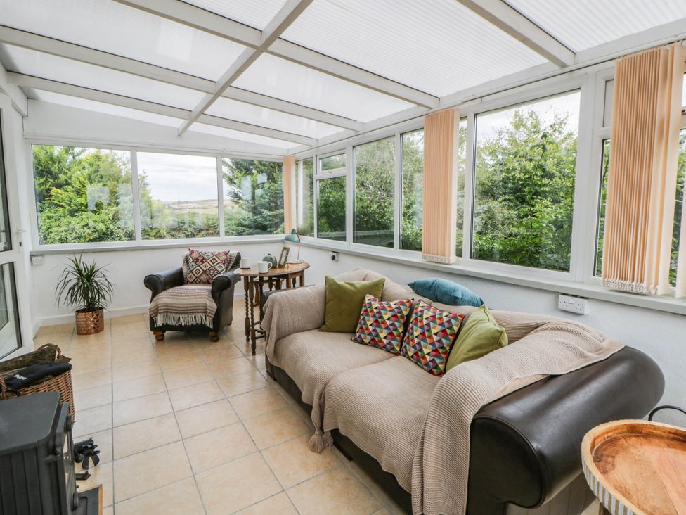 A conservatory with a sofa and armchair at Llain in Cardigan