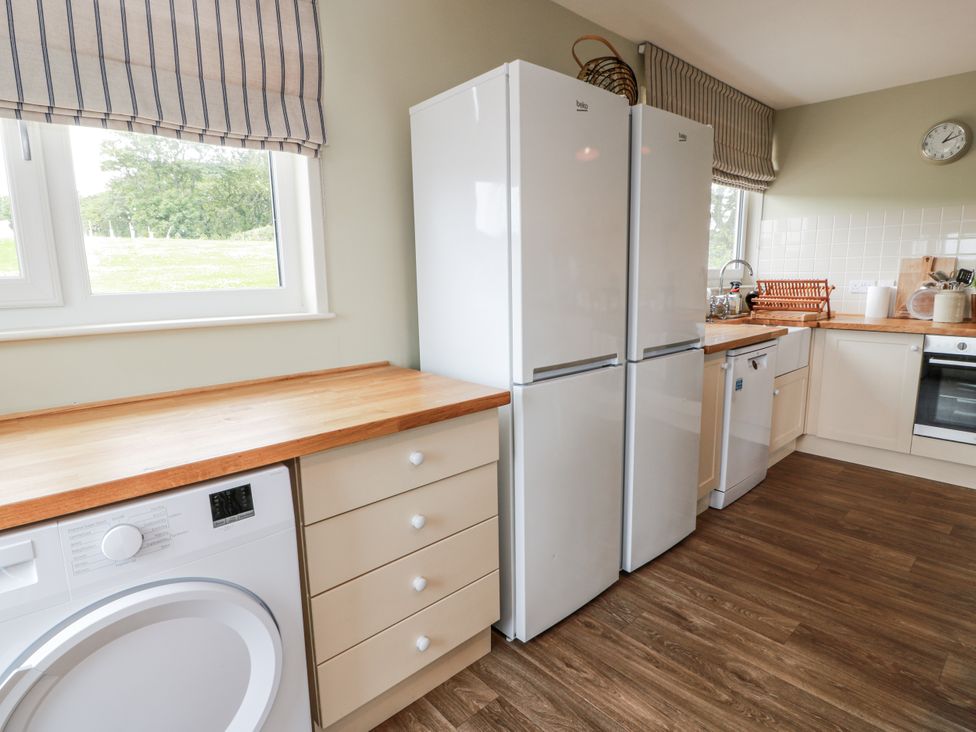 A kitchen with appliances including a refrigerator and washing machine at The Dairy in Newton Stewart