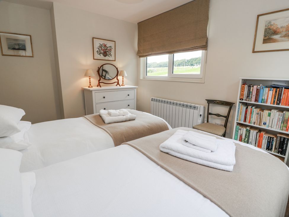 A bedroom with twin beds and a bookshelf at The Dairy in Newton Stewart