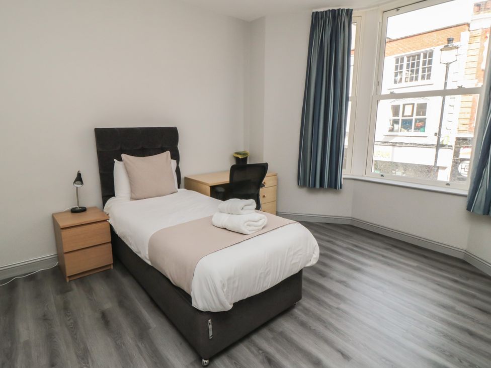 A bedroom with a bed, nightstand, desk and chair at The Newborough Apartment 2 in Scarborough