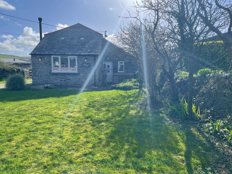A house with grass and trees outside Puffin Cottage in Tintagel