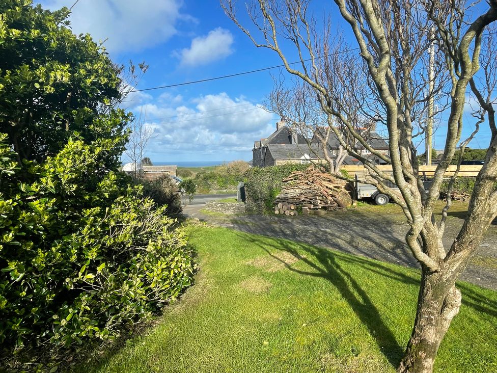 A garden with bushes and a view of a house at Puffin Cottage in Tintagel