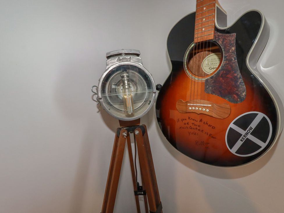 A guitar and a lamp on a wooden tripod at Puffin Cottage in Tintagel