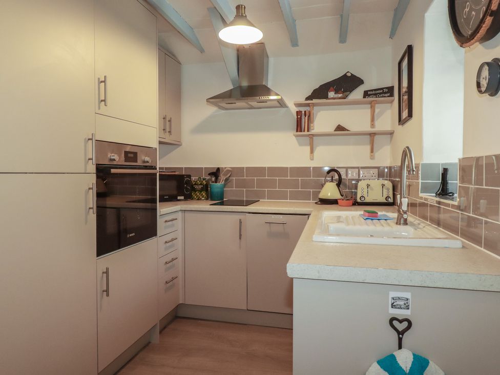 A kitchen with cabinets and appliances at Puffin Cottage in Tintagel