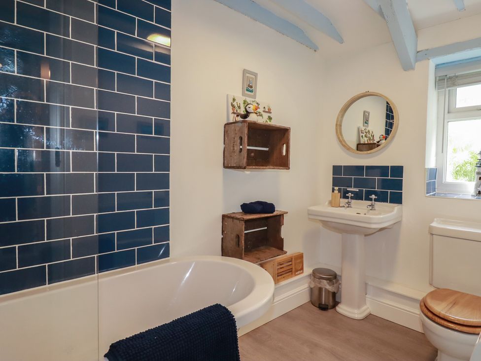 A bathroom with a bath tub and sink at Puffin Cottage in Tintagel
