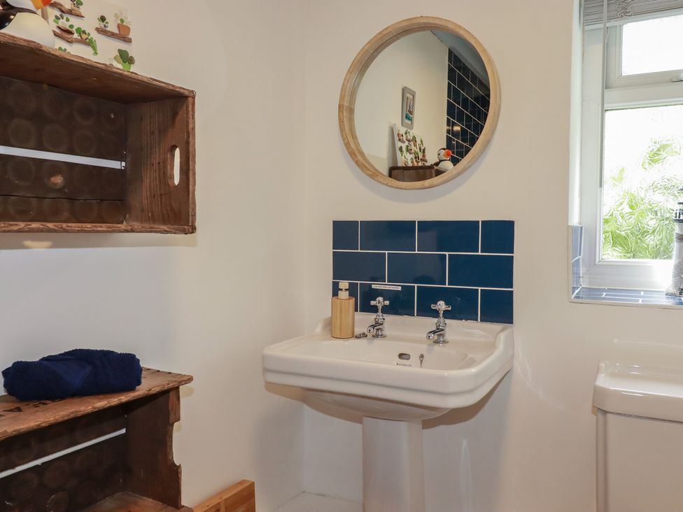 A bathroom with a sink and mirror at Puffin Cottage in Tintagel