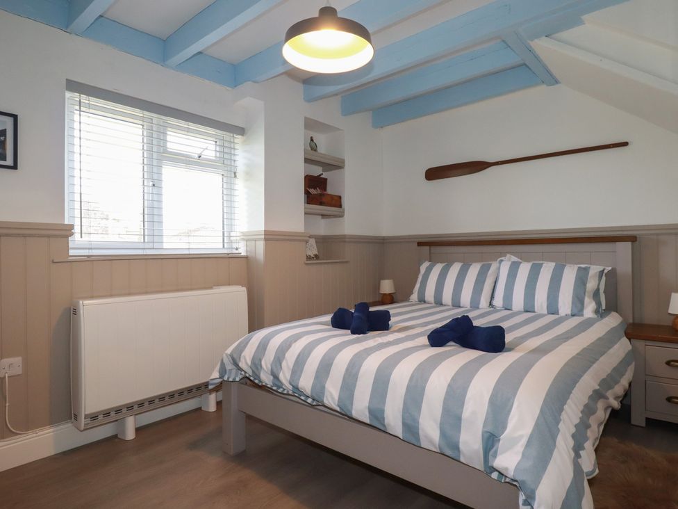 A bedroom with a bed and shelves at Puffin Cottage in Tintagel