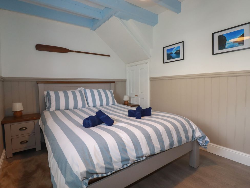 A bedroom with a striped bed and bedside tables at Puffin Cottage in Tintagel
