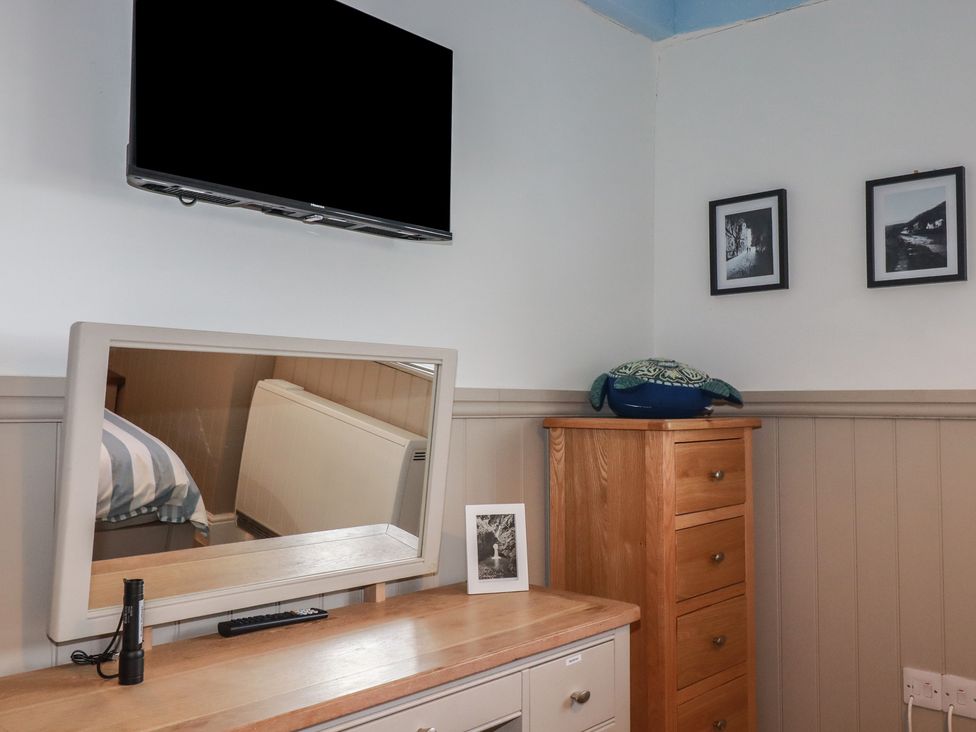 A bedroom with a television and a mirror at Puffin Cottage in Tintagel