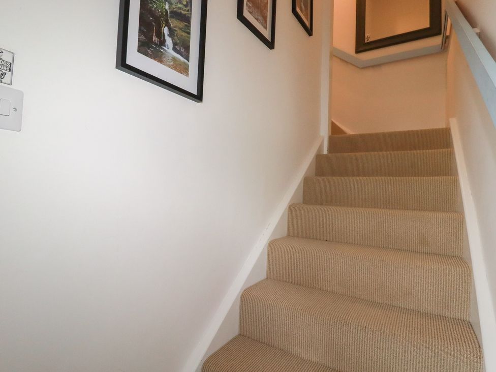 A staircase with framed pictures on the wall at Puffin Cottage in Tintagel